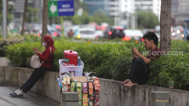 Pedagang duduk di area trotoar kawasan Sudirman, Jakarta, Rabu (2/2/2022). [Suara.com/Angga Budhiyanto]