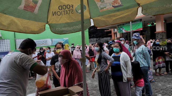 Warga mengantre untuk membeli sembako murah di Kantor Kelurahan Cililitan, Jakarta, Rabu (2/2/2022). [Suara.com/Angga Budhiyanto]