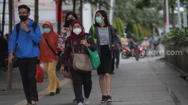 Sejumlah pekerja berjalan di trotoar kawasan Sudirman, Jakarta, Rabu (2/2/2022). [Suara.com/Angga Budhiyanto]
