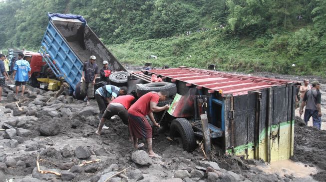 Warga membantu proses evakuasi truk yang terjebak banjir lahar di aliran Sungai Boyong, Sleman, DI Yogyakarta, Kamis (3/2/2022).  ANTARA FOTO/Hendra Nurdiyansyah