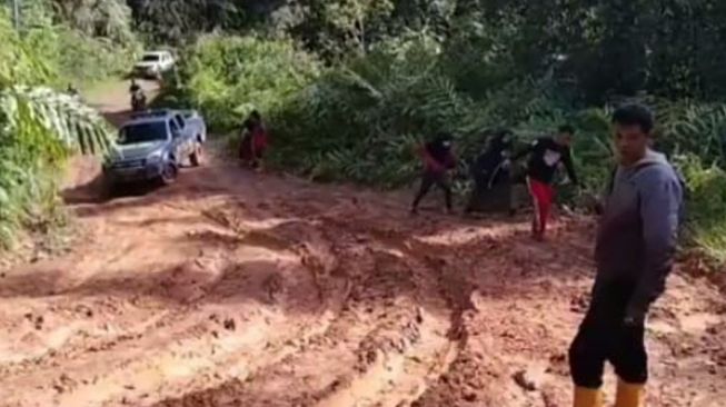 Aiptu Muhammad Agus terpaksa turun melihat keadaan jalan yang berlumpur saat monitoring vaksinasi di Nagari Garabak Data, Kecamatan Tigo Lurah, Kabupaten Solok. [Dok.Istimewa]