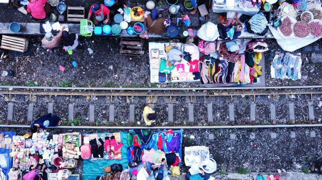 Foto udara suasana pedagang berjualan di pinggir rel kereta api di Surabaya, Jawa Timur, Jumat (4/2/2022).  ANTARA FOTO/Patrik Cahyo Lumintu
