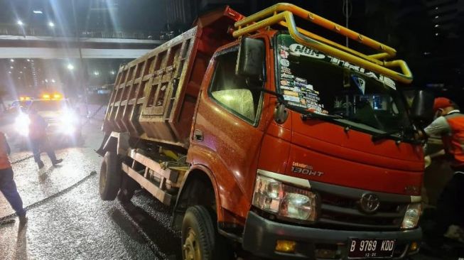 Petugas mengevakuasi jenazah kernet truk berinsial MR (26) yang tewas tertimpa mobil saat ganti ban di Tol TB Simatupang, Jakarta Selatan, Jumat (4/2/2022). [Dok. Polisi]