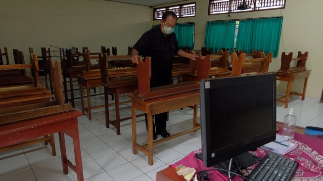 Petugas merapikan kursi di ruang kelas SMP Negeri 3 Denpasar, Bali, Jumat (4/2/2022). ANTARA FOTO/Nyoman Hendra Wibowo
