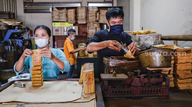 Sejumlah pekerja memasukan kopi ke bungkusnya di Toko Kopi Sari Murni, Jatinegara, Jakarta Timur, Sabtu (5/2/2022). [Suara.com/Alfian Winanto]