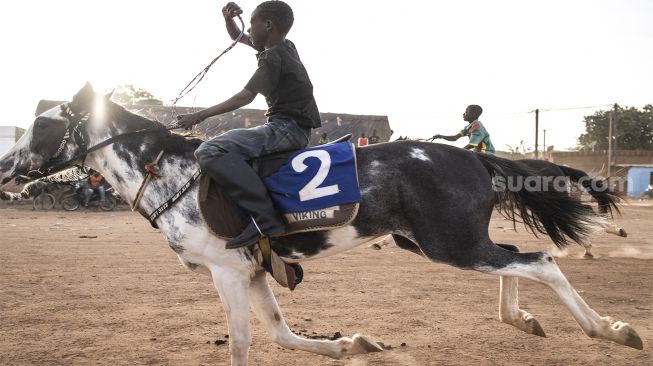 Seorang Joki muda saat mengikuti pertandingan balap kuda di Kota Ouagadougou, Burkina Faso, Senin (30/1/2022). [Photo by JOHN WESSELS / AFP]