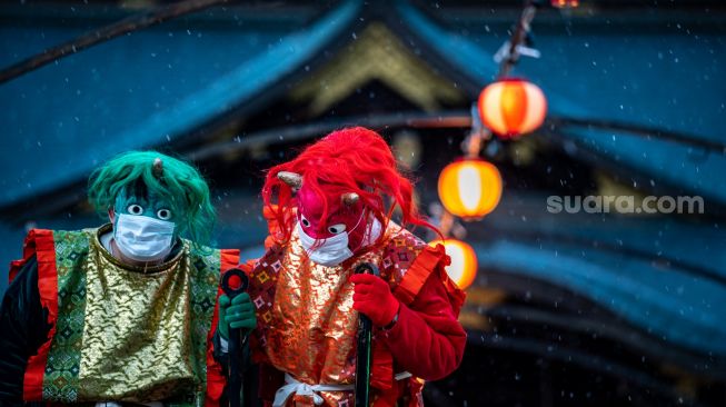 Penampil yang mengenakan topeng monster dan kostum 'oni' berkumpul untuk tradisi 'Mamemaki' saat perayaan Setsubun di Kuil Fukushima Inari, Jepang, (3/2/2022). [Photo by Philip FONG / AFP]