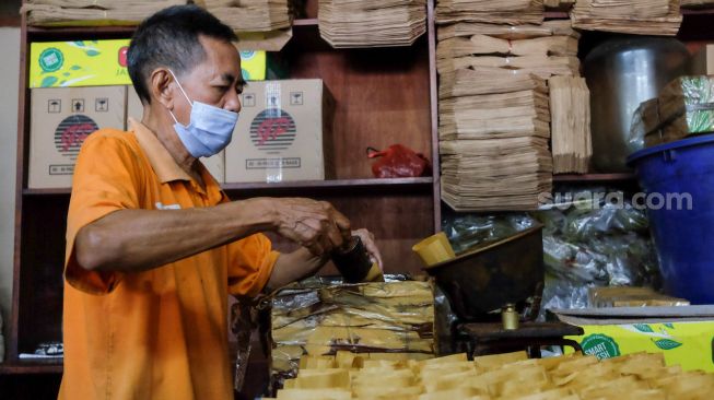 Seorang pekerja memasukan kopi ke bungkusnya di Toko Kopi Sari Murni, Jatinegara, Jakarta Timur, Sabtu (5/2/2022). [Suara.com/Alfian Winanto]