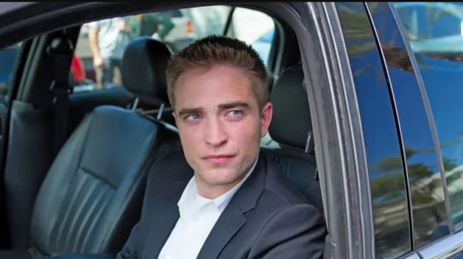 Robert Pattinson pose saat menyetir sebuah mobil di film (Popsugar)