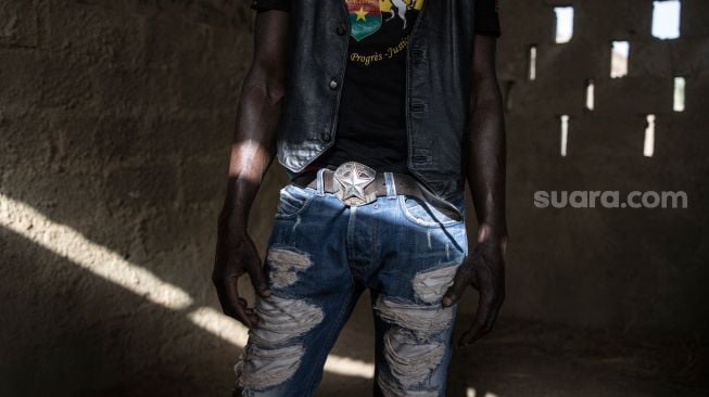 Joki bernama Faso Alli memamerkan fashion layaknya  koboi  saat difoto di Kandang kudanya di Kota Ouagadougou, Burkina Faso, Selasa (1/2/2022). [Photo by JOHN WESSELS / AFP]