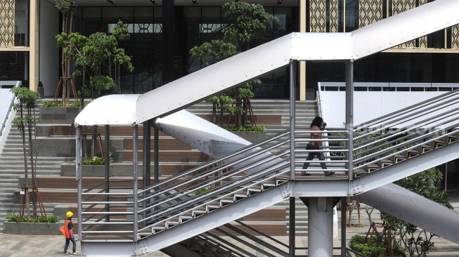 Warga berjalan di jembatan penyeberangan orang (JPO) sekitar Gedung Sarinah, Jakarta, Minggu (6/2/2022). [Suara.com/Angga Budhiyanto] 