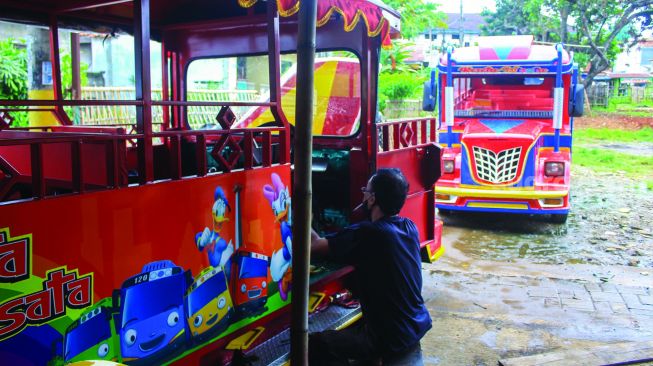 Pekerja menyelesaikan pembuatan odong-odong di Pondok Aren, Tangerang Selatan, Banten, Minggu (6/2/2022).  [Suara.com/Septian]
