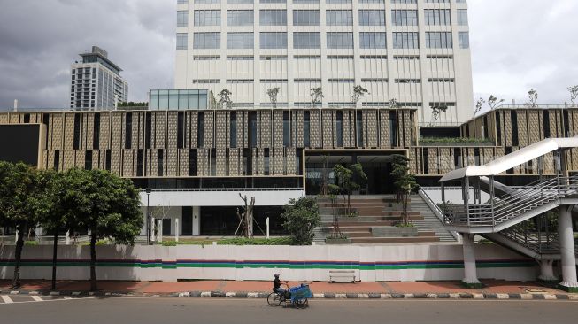 Pedagang melintas di depan Gedung Sarinah, Jakarta, Minggu (6/2/2022). [Suara.com/Angga Budhiyanto] 