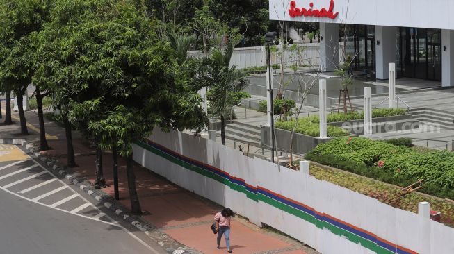 Pejalan kaki melintas di depan Gedung Sarinah, Jakarta, Minggu (6/2/2022). [Suara.com/Angga Budhiyanto] 