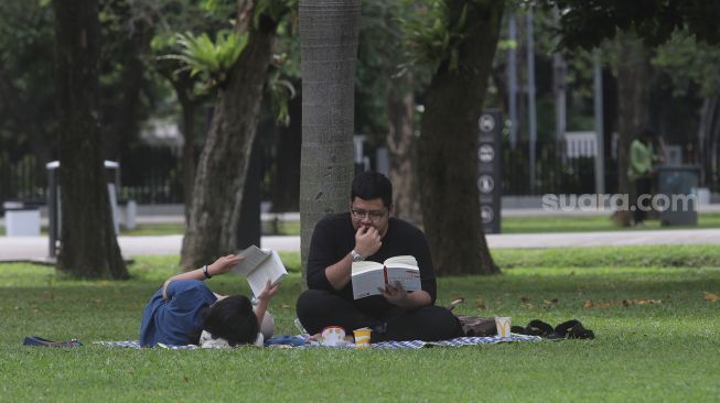 Warga membaca buku di Taman Lapangan Banteng, Jakarta, Minggu (6/2/2022). [Suara.com/Angga Budhiyanto]