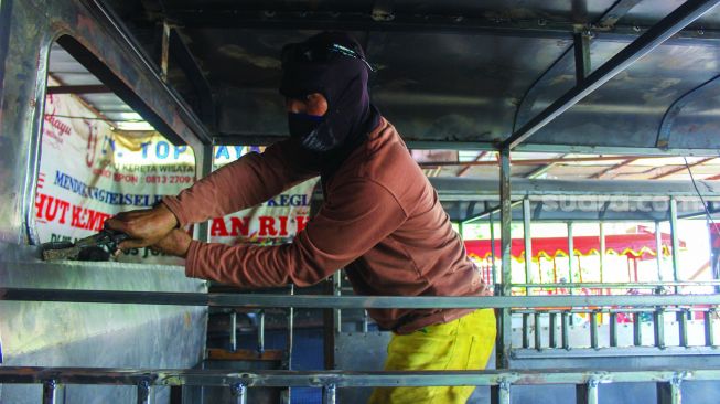 Pekerja menyelesaikan pembuatan odong-odong di Pondok Aren, Tangerang Selatan, Banten, Minggu (6/2/2022).  [Suara.com/Septian]
