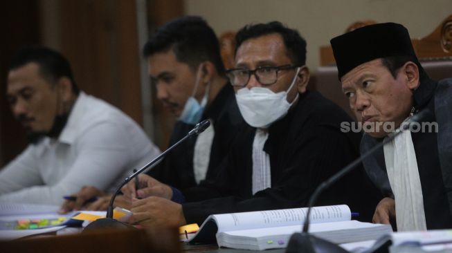 Kuasa Hukum Terdakwa yang juga musisi I Gede Ari Astina atau Jerinx Superman is Dead (SID), Sugeng Teguh Santoso (kanan) mendengarkan keterangan dari saksi ahli selama sidang lanjutan kasus pengancaman melalui media elektronik pada Adam Deni di Pengadilan Negeri (PN) Jakarta Pusat, Jakarta, Senin (7/2/2022). [Suara.com/Angga Budhiyanto]