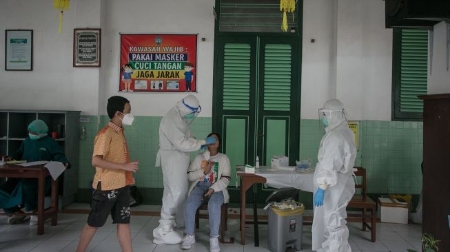 Petugas Dinas Kesehatan mengambil sampel lendir hidung dan tenggorokan siswa yang kontak erat dengan siswa terkonfirmasi positif COVID-19 untuk dilakukan tes Swab PCR di SD Marsudirini, Solo, Jawa Tengah, Senin (7/2/2022).  ANTARA FOTO/Mohammad Ayudha