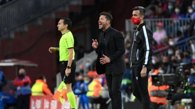 Pelatih Atletico Madrid Diego Simeone memberi instruksi dari pinggir lapangan saat timnya menghadapi Barcelona di Camp Nou, Minggu (6/2/2022). [AFP]