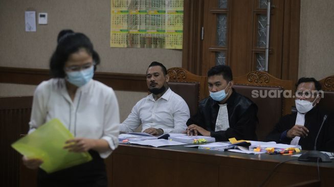 Terdakwa yang juga musisi I Gede Ari Astina atau Jerinx Superman is Dead (SID) (kedua kiri) bersiap menjalani sidang lanjutan kasus pengancaman melalui media elektronik pada Adam Deni dengan agenda mendengarkan keterangan dari saksi ahli di Pengadilan Negeri (PN) Jakarta Pusat, Jakarta, Senin (7/2/2022). [Suara.com/Angga Budhiyanto]