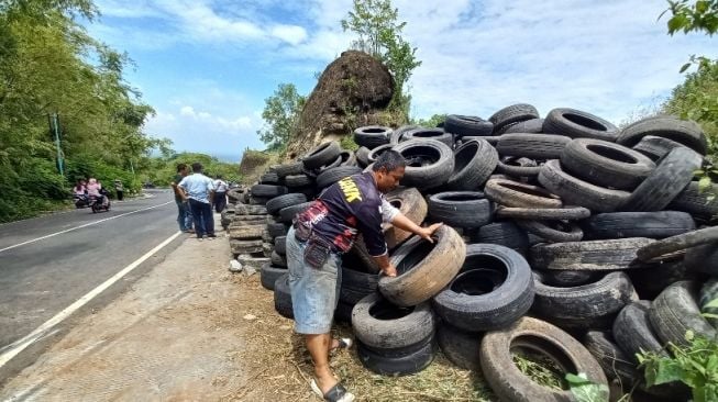 Anggota Trail Adventure Bantul IOF 2x1 Rus Susanto menata ban bekas di Bukit Bego, Wukirsari, Imogiri, Bantul, pada Selasa (8/2/2022). (SuaraJogja.id/Rahmat Jiwandono)