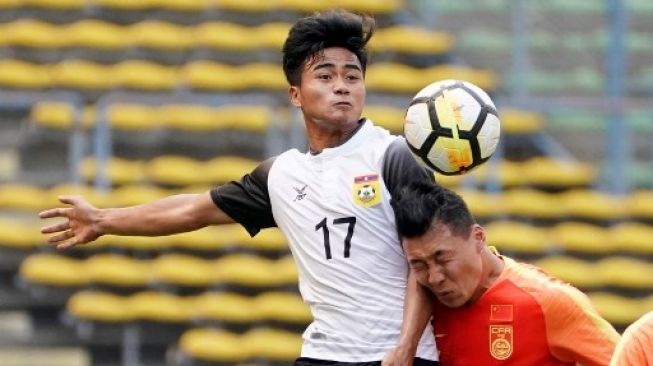 Bounphachan Bounkong dari Laos berebut bola dengan Li Yang (kanan) dari China selama pertandingan sepak bola kualifikasi Asia Olimpiade Tokyo 2020 antara China dan Laos di Shah Alam, di pinggiran Kuala Lumpur, pada 22 Maret 2019.KAMARUL AKHIR/AFP