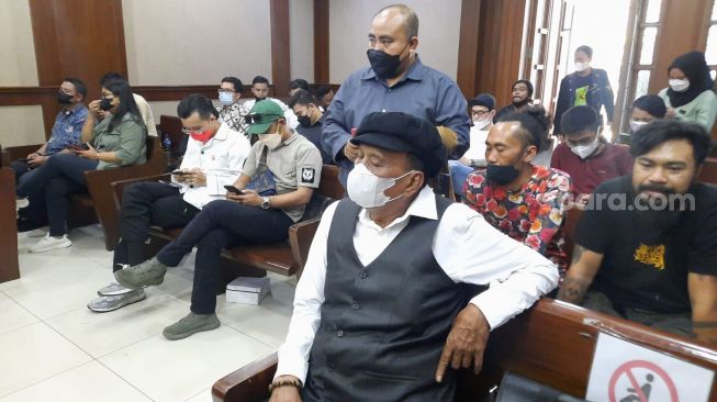 Dokter Tirta (masker merah) dan ayah Jerinx (masker putih), I Wayan Arjono di sidang Jerinx, Pengadilan Negeri Jakarta Pusat, Rabu (9/2/2022). [Suara.com/Evi Ariska]