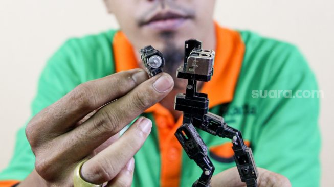 Seto Krisna Putra saat membuat miniatur robot dari limbah korek gas di Pinang Ranti, Jakarta Timur, Kamis (10/2/2022). [Suara.com/Alfian Winanto]