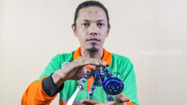 Seto Krisna Putra memamerkan miniatur robot dari limbah korek gas hasil buatannya di Pinang Ranti, Jakarta Timur, Kamis (10/2/2022). [Suara.com/Alfian Winanto]