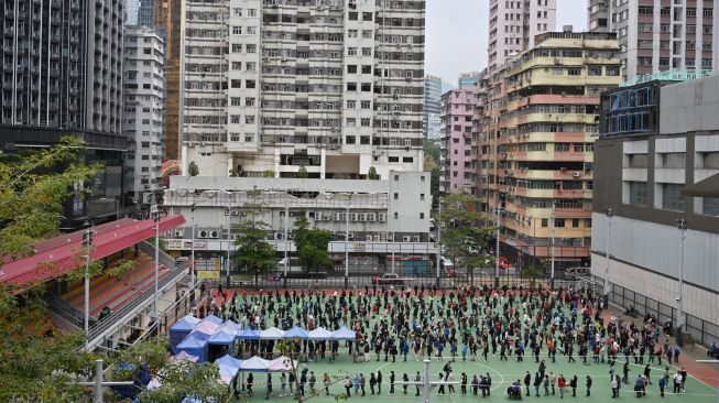 Suasana di stasiun pengumpulan spesimen bergerak untuk pengujian Covid-19 yang dipadati warga di Distrik Tung Chung, Hong Kong, Kamis (10/2/2022). [Peter PARKS / AFP]