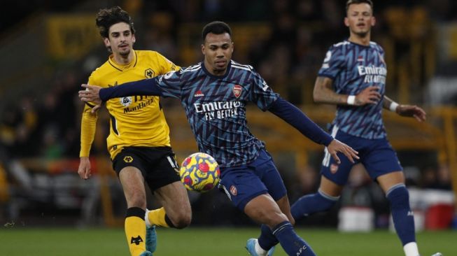 Pemain belakang Arsenal asal Brasil, Gabriel (tengah) bersaing dengan striker Wolverhampton Wanderers Francisco Trincao (kiri) selama pertandingan pekan ke-24 Liga Inggris antara Wolves vs Arsenal di stadion Molineux, Jumat (11/2/2022) dini hari WIB.Adrian DENNIS / AFP.