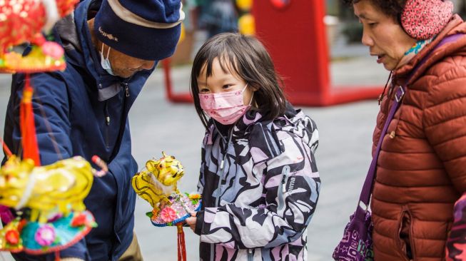 Seorang anak memegang lentera menjelang festival lampion di Nanjing, China, Kamis (10/2/2022). [STR/AFP]