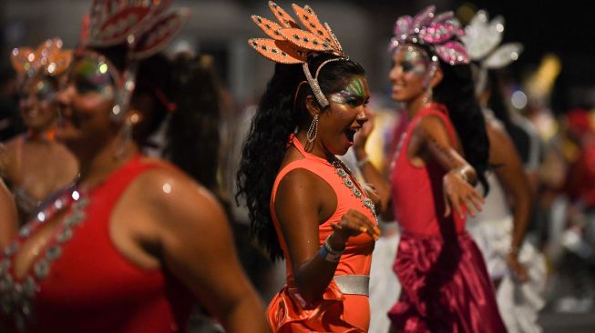 Para penari yang dikenal sebagai 'komparsa' bersaing dengan dengan memainkan musik dan tarian tradisional 'candombe' saat festival 'Las Llamadas' di Montevideo, Uruguay, Kamis (10/2/2022). [PABLO PORCIUNCULA / AFP]