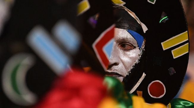 ara penabuh drum yang dikenal sebagai 'komparsa' berdandan sebelum bersaing dengan dengan memainkan musik dan tarian tradisional 'candombe' saat festival 'Las Llamadas' di Montevideo, Uruguay, Kamis (10/2/2022). [PABLO PORCIUNCULA / AFP]
