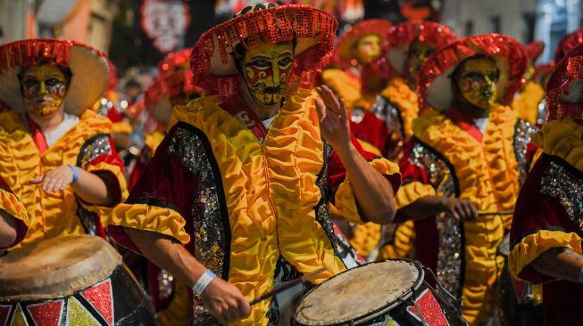 Para penabuh drum yang dikenal sebagai 'komparsa' bersaing dengan memainkan musik dan tarian tradisional 'candombe' saat festival 'Las Llamadas' di Montevideo, Uruguay, Kamis (10/2/2022). [PABLO PORCIUNCULA / AFP]