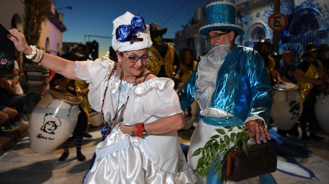 Para penari yang dikenal sebagai 'komparsa' bersaing dengan dengan memainkan musik dan tarian tradisional 'candombe' saat festival 'Las Llamadas' di Montevideo, Uruguay, Kamis (10/2/2022). [PABLO PORCIUNCULA / AFP]