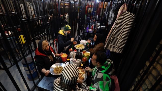 Pengunjung makan malam di restoran "Cell 16' yang berkonsep penjara di Teheran, Iran, Jumat (4/2/2022). [ATTA KENARE / AFP]