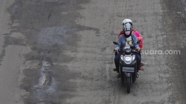 Kendaraan bermotor melewati jalan berlubang di Jalan Rasuna Said, Kuningan, Jakarta, Minggu (13/2/2022). [Suara.com/Angga Budhiyanto]