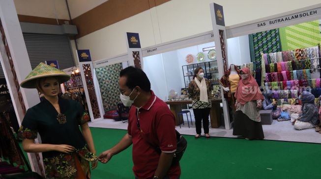 Pengunjung melihat koleksi kain tradisional saat Pameran Adiwastra Nusantara di Jakarta Convention Center (JCC), Jakarta, Minggu (13/2/2022). [Suara.com/Angga Budhiyanto]