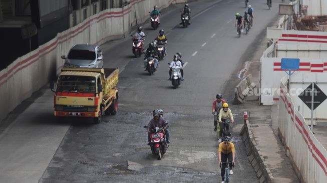 Sejumlah pesepeda melewati jalan berlubang di Jalan Rasuna Said, Kuningan, Jakarta, Minggu (13/2/2022). [Suara.com/Angga Budhiyanto]