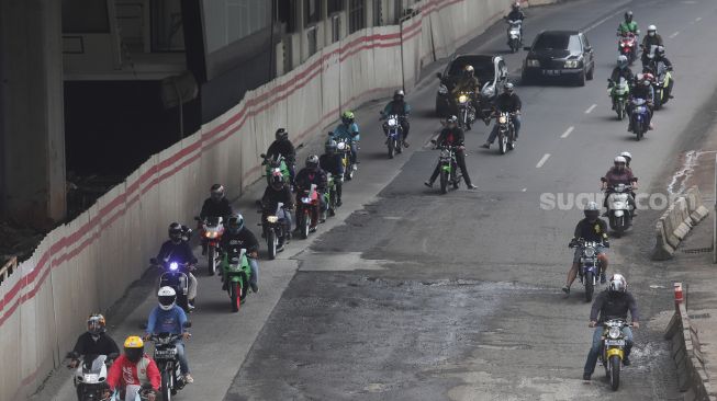 Kendaraan bermotor melewati jalan berlubang di Jalan Rasuna Said, Kuningan, Jakarta, Minggu (13/2/2022). [Suara.com/Angga Budhiyanto]