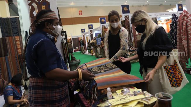 Pengunjung melihat koleksi kain tradisional saat Pameran Adiwastra Nusantara di Jakarta Convention Center (JCC), Jakarta, Minggu (13/2/2022). [Suara.com/Angga Budhiyanto]