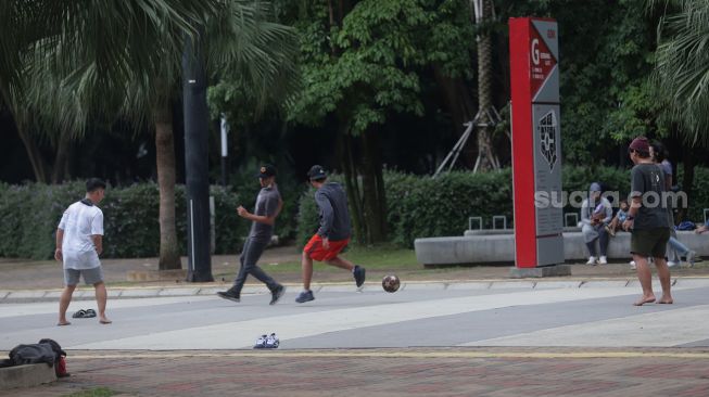 Warga bermain sepak bola di kompleks Gelora Bung Karno, Senayan, Jakarta, Minggu (13/2/2022). [Suara.com/Angga Budhiyanto]