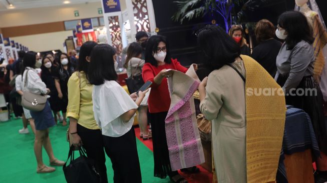 Pengunjung melihat koleksi kain tradisional saat Pameran Adiwastra Nusantara di Jakarta Convention Center (JCC), Jakarta, Minggu (13/2/2022). [Suara.com/Angga Budhiyanto]