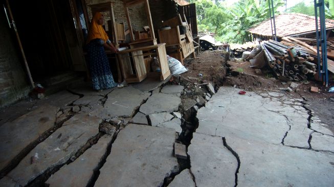 Seorang warga menunjukkan lantai rumah yang rusak parah akibat bencana tanah bergerak di Desa Dermasuci, Kabupaten Tegal, Jawa Tengah, Senin (14/2/2022).  ANTARA FOTO/Oky Lukmansyah