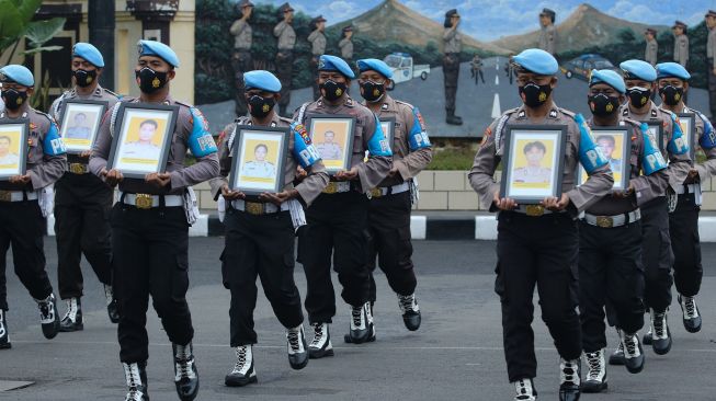 Polisi membawa foto anggota Polri yang diberhentikan saat upacara pemberhentian tidak dengan hormat (PTDH) di Polrestabes Surabaya, Jawa Timur, Senin (14/2/2022). ANTARA FOTO/Didik Suhartono
