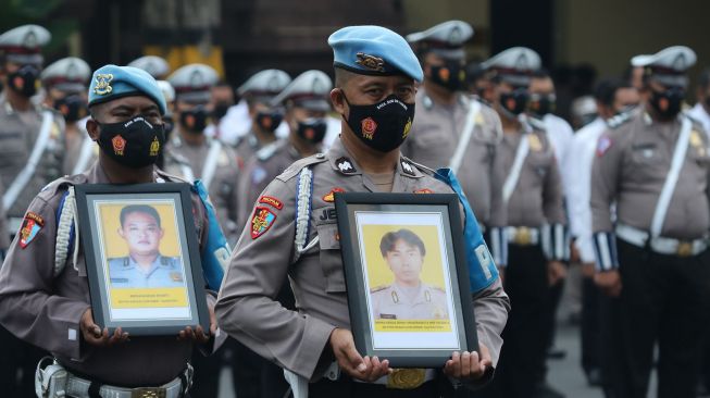 Polisi membawa foto anggota Polri yang diberhentikan saat upacara pemberhentian tidak dengan hormat (PTDH) di Polrestabes Surabaya, Jawa Timur, Senin (14/2/2022). ANTARA FOTO/Didik Suhartono
