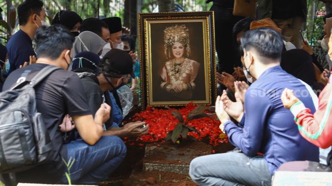 Keluarga berdoa di atas pusara Artis Dorce Gamalama usai dimakamkan di TPU Bantar Jati, Cipayung, Jakarta Timur, Rabu (16/2/2022). [Suara.com/Alfian Winanto]