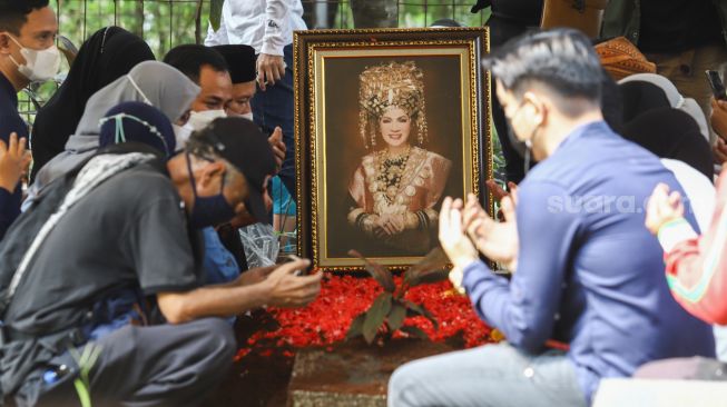 Keluarga berdoa di atas pusara Artis Dorce Gamalama usai dimakamkan di TPU Bantar Jati, Cipayung, Jakarta Timur, Rabu (16/2/2022). [Suara.com/Alfian Winanto]
