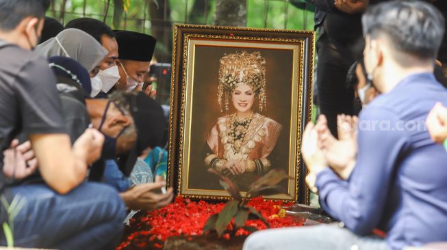 Keluarga berdoa di atas pusara Artis Dorce Gamalama usai dimakamkan di TPU Bantar Jati, Cipayung, Jakarta Timur, Rabu (16/2/2022). [Suara.com/Alfian Winanto]